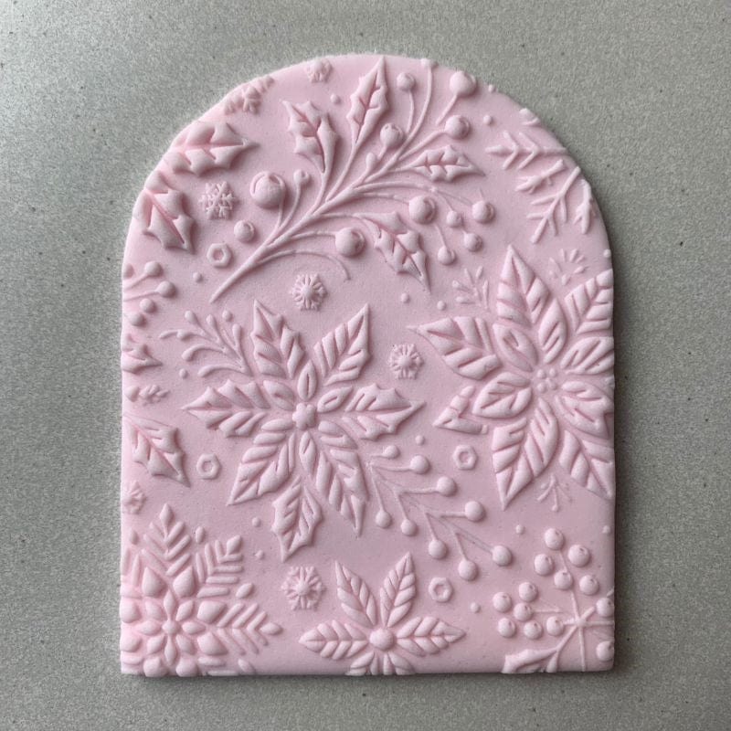 Arched fondant cookie embossed with Christmas floral design using an acrylic cookie stamp