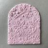 Arched fondant cookie embossed with Christmas floral design using an acrylic cookie stamp