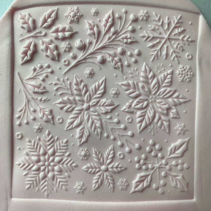 Square fondant cookie decorated with snowflakes and floral patterns from a Christmas embosser stamp