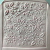 Square fondant cookie decorated with snowflakes and floral patterns from a Christmas embosser stamp