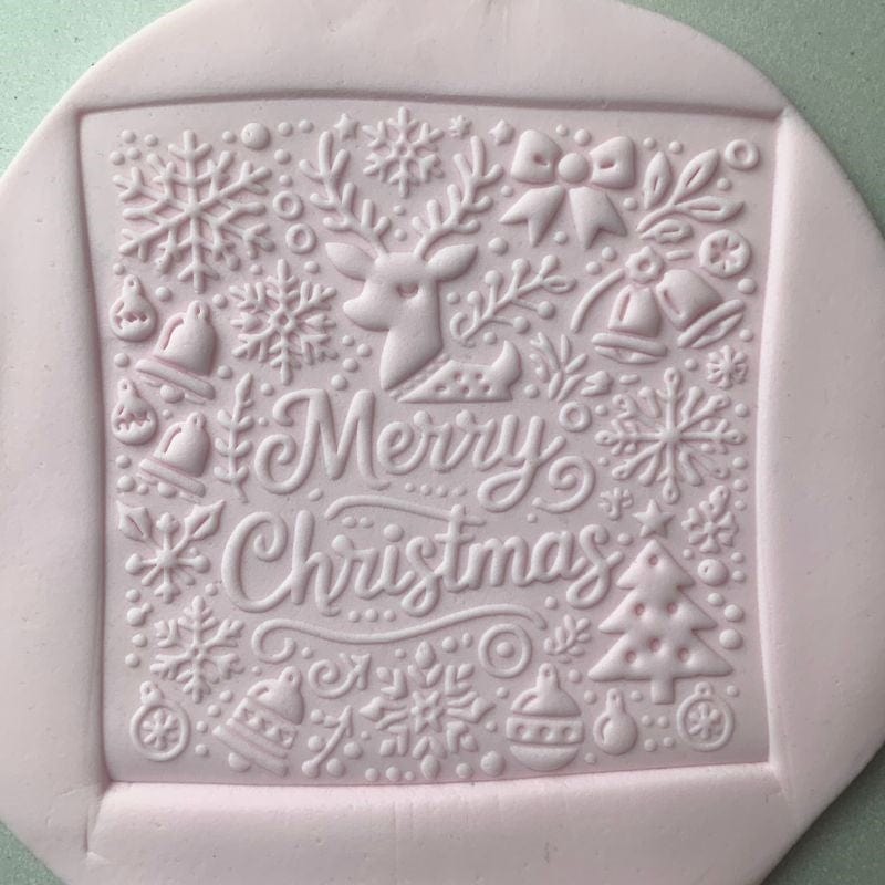 Square fondant cookie embossed with a reindeer and holiday patterns using a Christmas-themed embosser stamp
