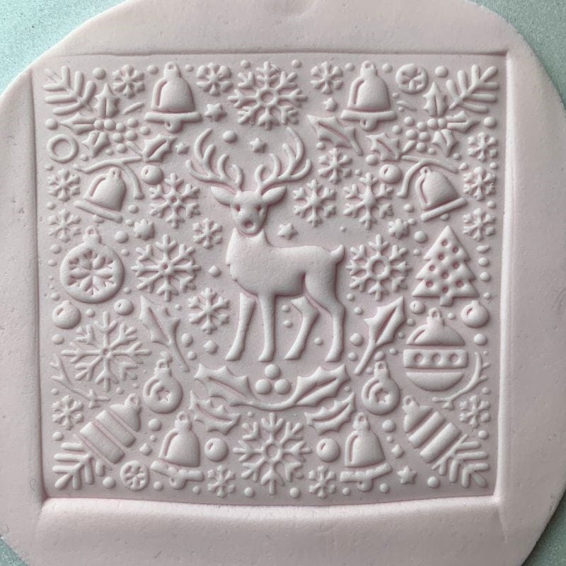 Square fondant cookie featuring a reindeer and holiday patterns using a Christmas embosser stamp