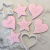 Pink fondant cookies stamped with YAY and Make a Wish, alongside cutters