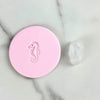 clear acrylic seahorse cookie stamp with fondant impression beside it