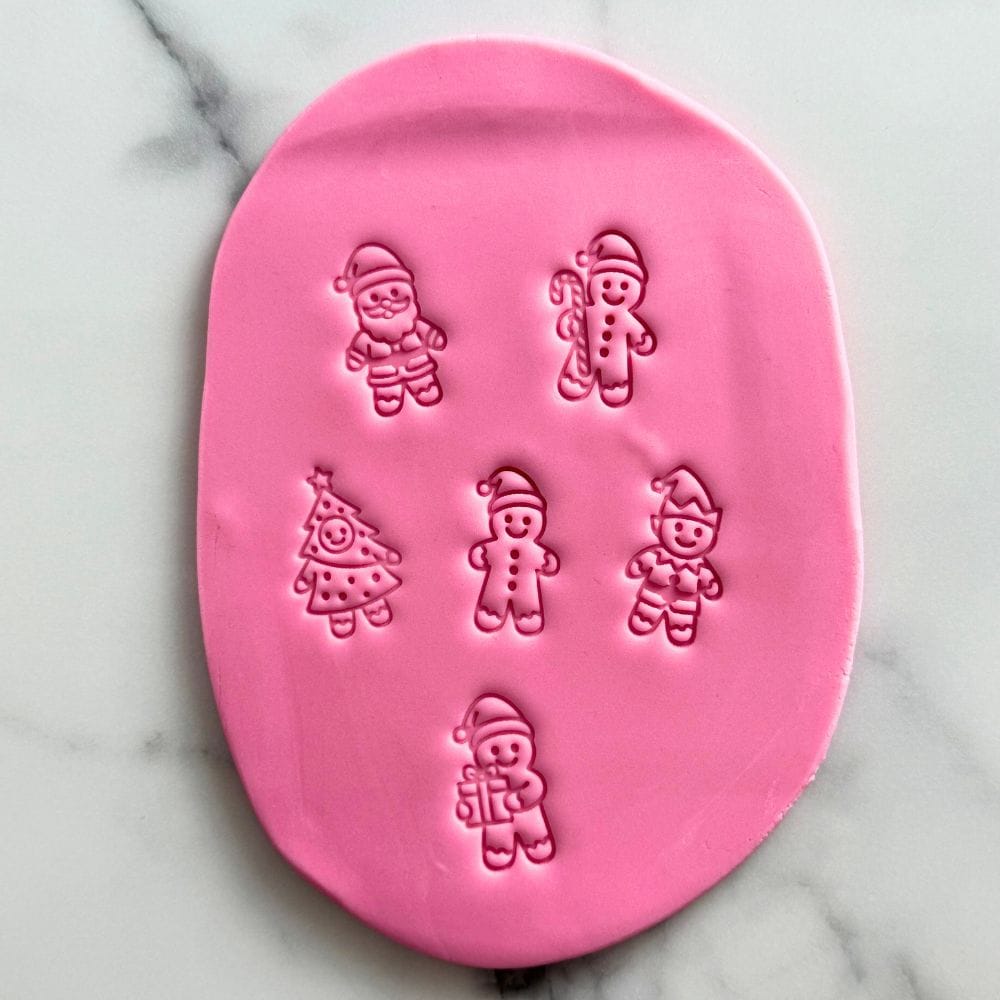 mini gingerbread character fondant cookie stamps pressed into pink fondant