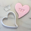 Heart cookie cutter with mini YAY fondant stamp on pink cookie.